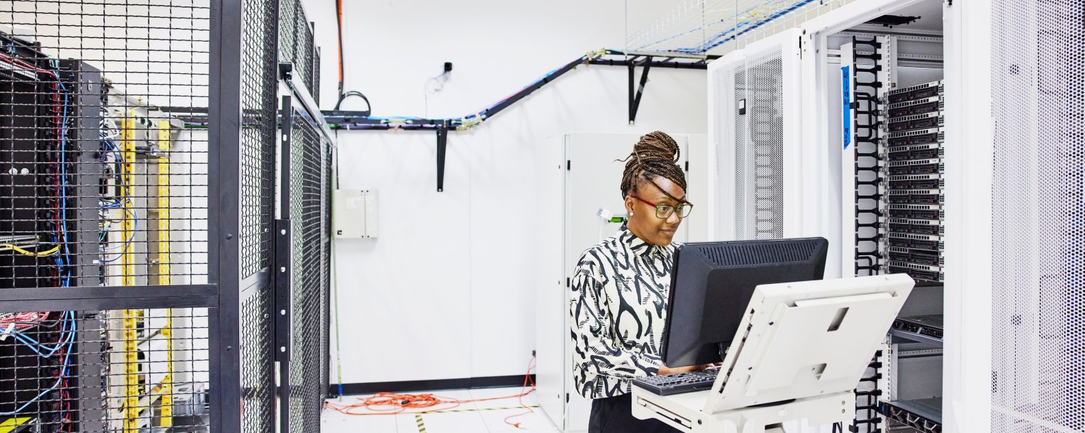 An IT administrator in a data center looks into a laptop computer