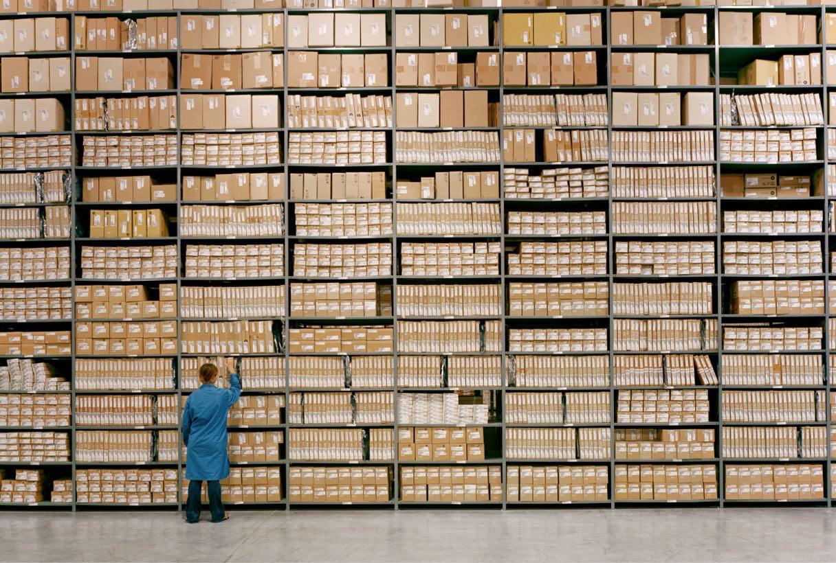 Woman retrieving a box from an inventory warehouse with hundreds items.
