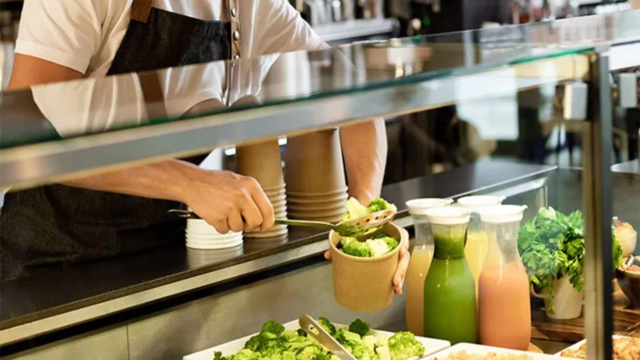 Une personne se servant une salade à un buffet