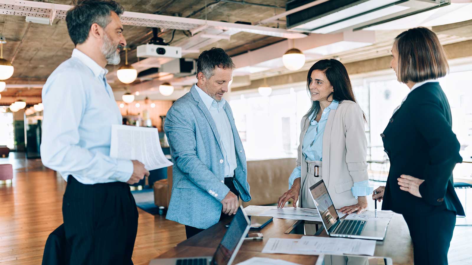 Quatre personnes en tenue d’affaires discutant debout autour d’une petite table