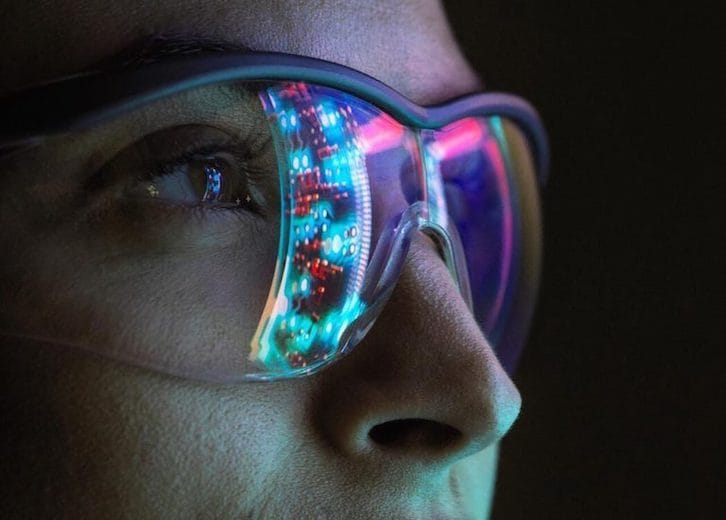 A person wearing glasses reflecting a screen