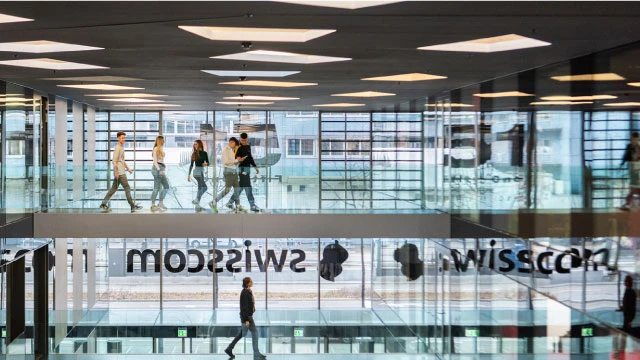 ガラス張りの建物の中を数人が歩くオフィス