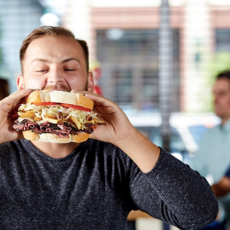 Personne prenant une bouchée d’un gros sandwich
