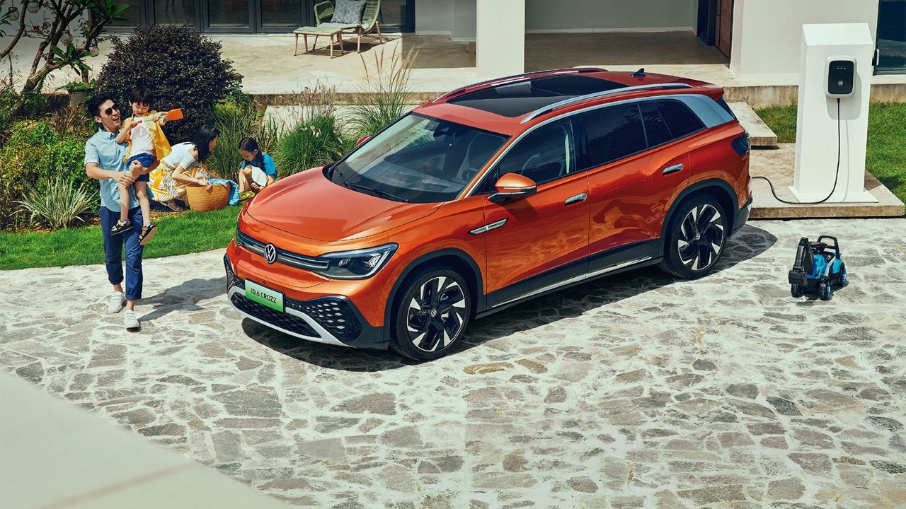 해변에서 하루를 보내기 위해 오렌지색 Volkswagen SUV에 짐을 싣는 젊은 가족