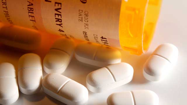 Comprimés blancs à côté du flacon de pilules sur ordonnance