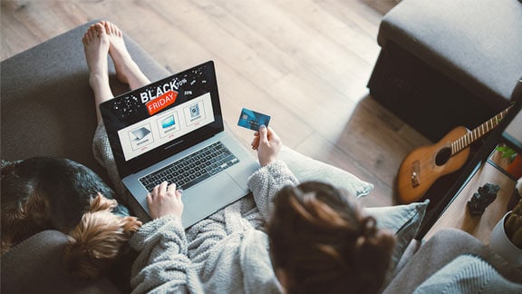 Vue aérienne d’une personne sur un ordinateur portable alors qu’elle tient une carte de crédit sur le canapé