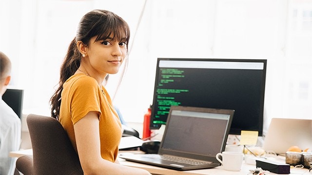 Jeune femme assise à un bureau programmant sur un ordinateur portable
