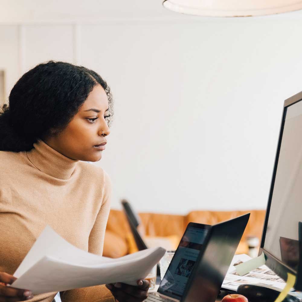 Female holding papers and looking at computer screen