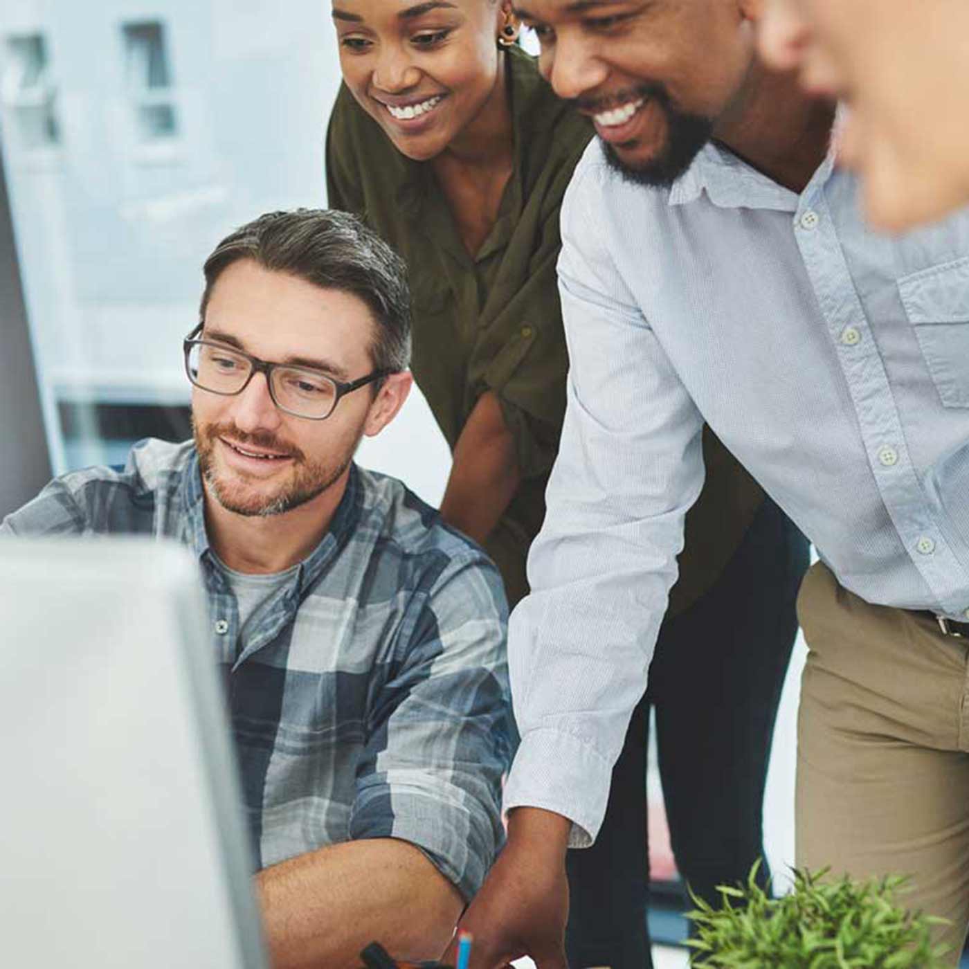 A group of colleagues working together on a computer in a modern office