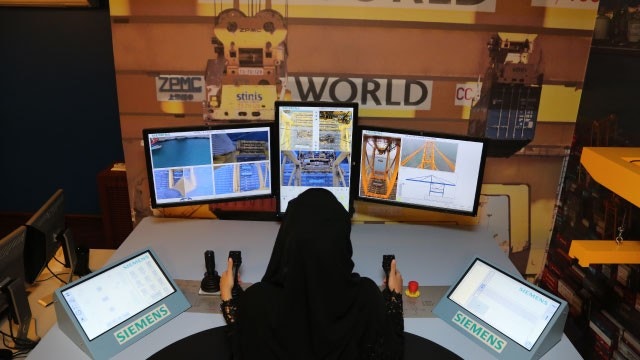 Une employée conduisant à distance une grue pour conteneurs maritimes