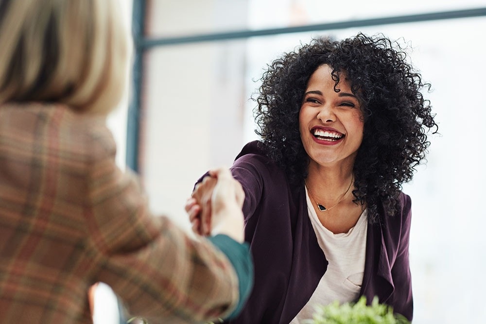 Woman with a big smile on her face shaking hands with someone