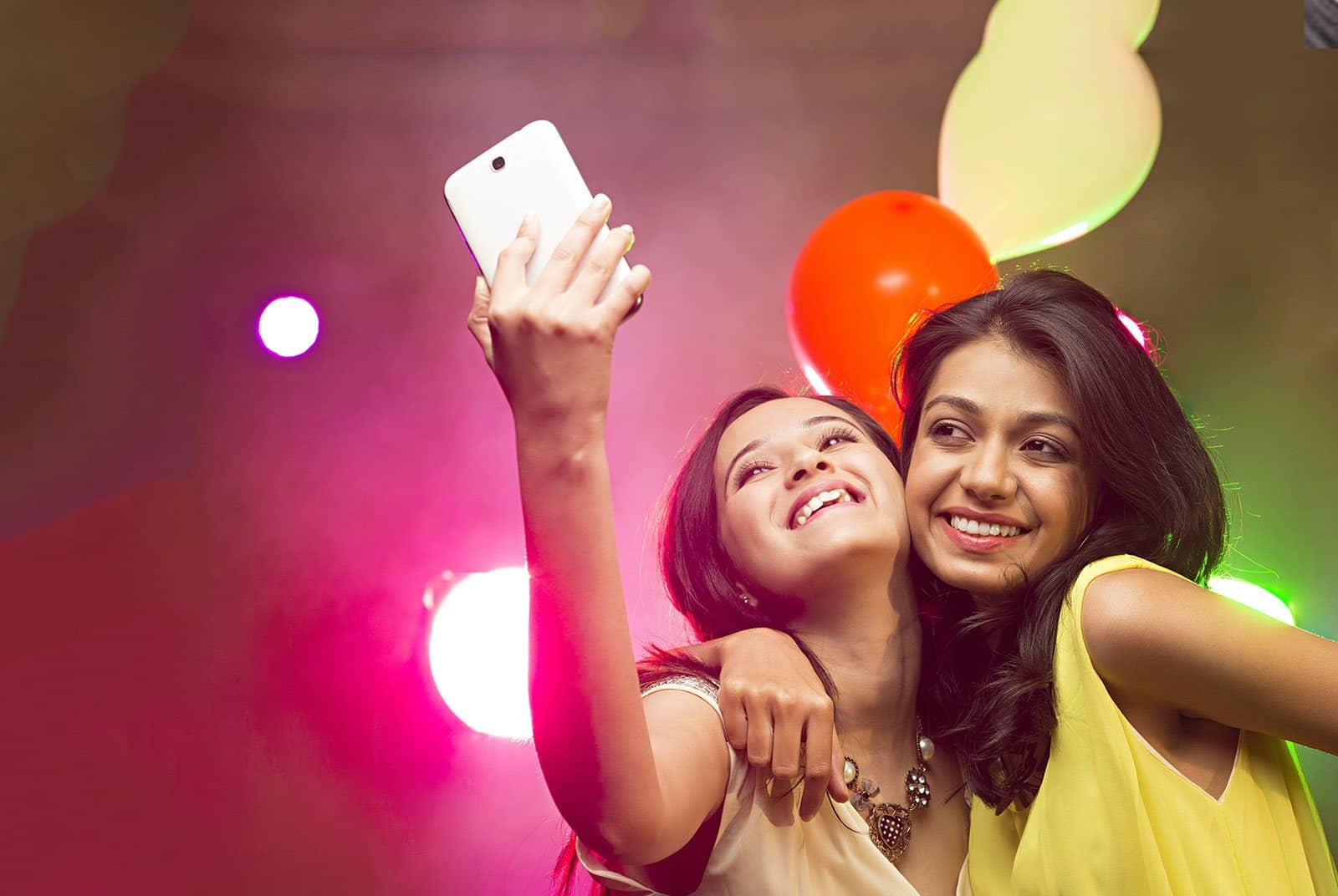 Deux belles femmes prenant un selfie avec une fête de festival en arrière-plan