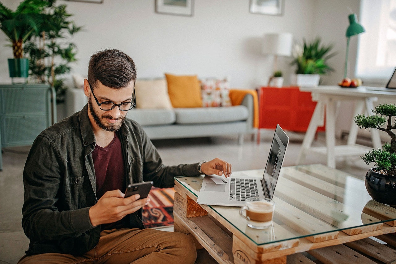 Men text messaging with smart phone, working from home