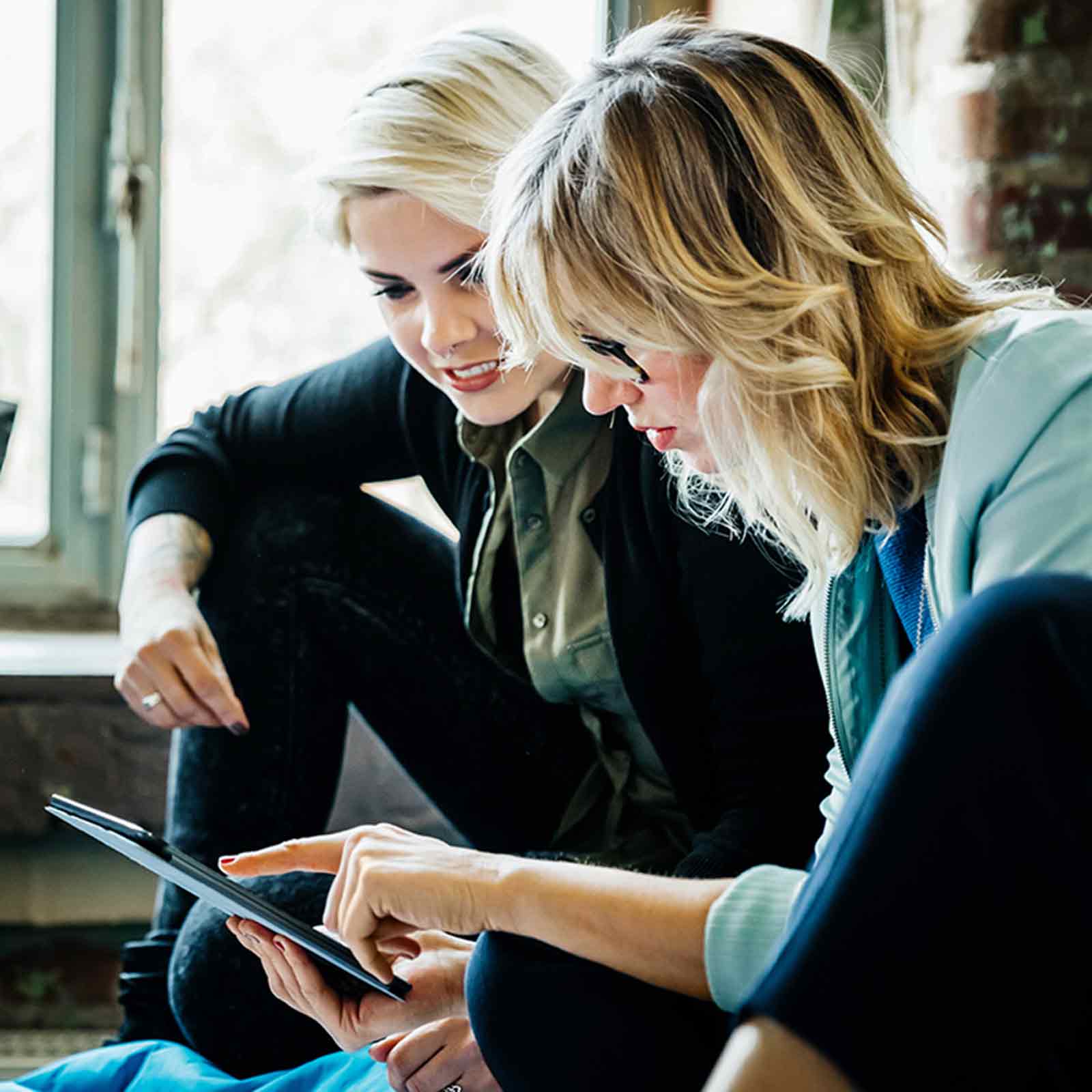 Tres mujeres de negocios sentadas en almohadas grandes en una oficina y hablando durante una reunión informal