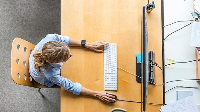 Femme assise devant son bureau travaillant sur son ordinateur