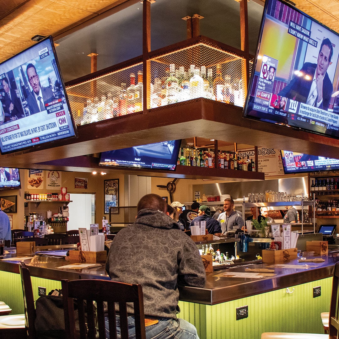 Intérieur d'un restaurant, avec des télévisions au-dessus d’un bar
