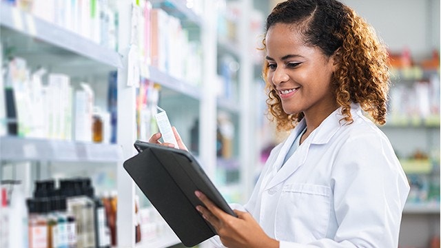 薬局で働きながら商品をチェックする薬剤師