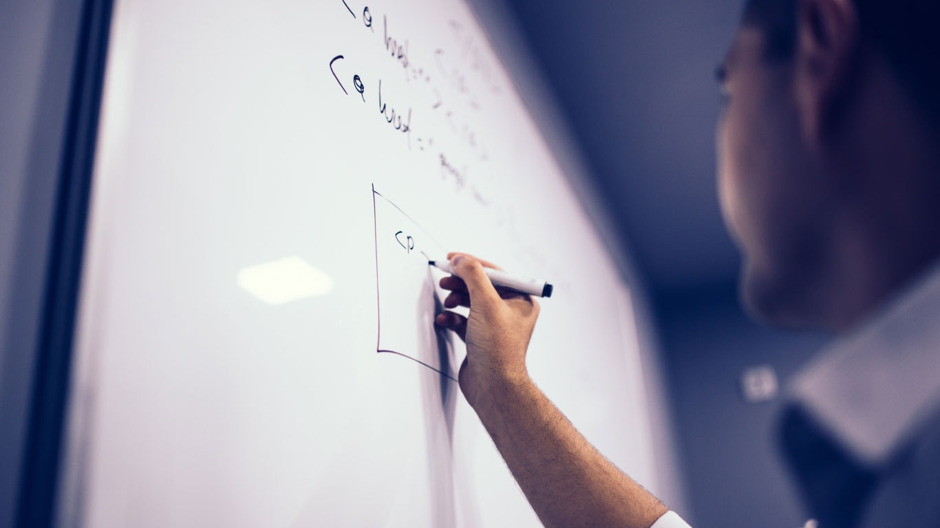 Homme dessinant un diagramme sur un tableau blanc