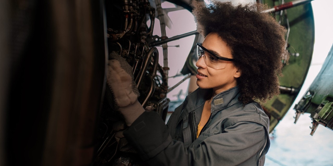 Person wearing safety goggles working on a large mechanical system