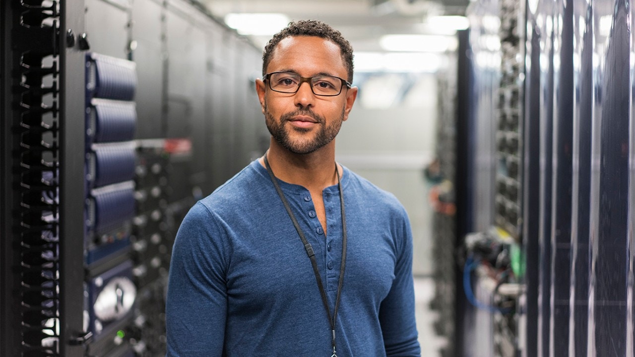 Technicien posant dans une salle de serveurs informatiques