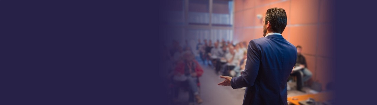 Homem falando em público para uma grande plateia