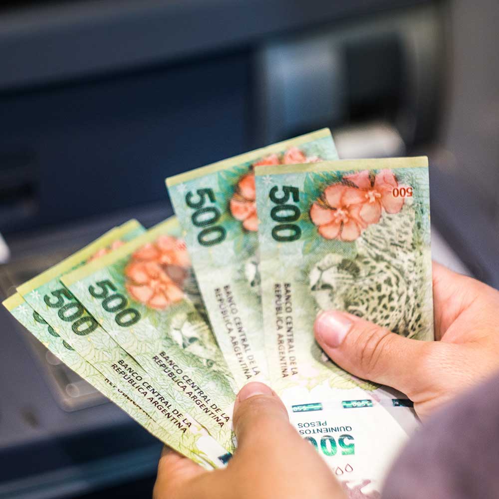 Main tenant plusieurs billets de 500 pesos argentins