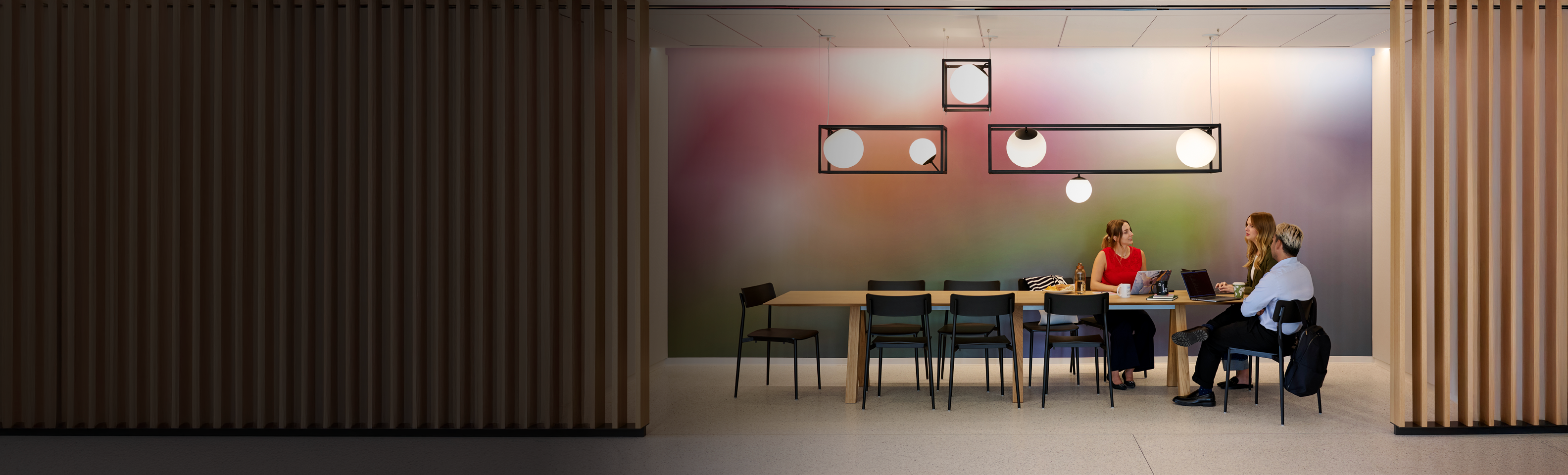 Three coworkers discussing ideias on their computers in a meeting room