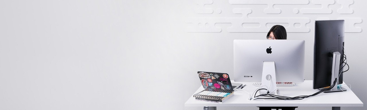 Pessoa sentada atrás de um monitor grande digitando no computador