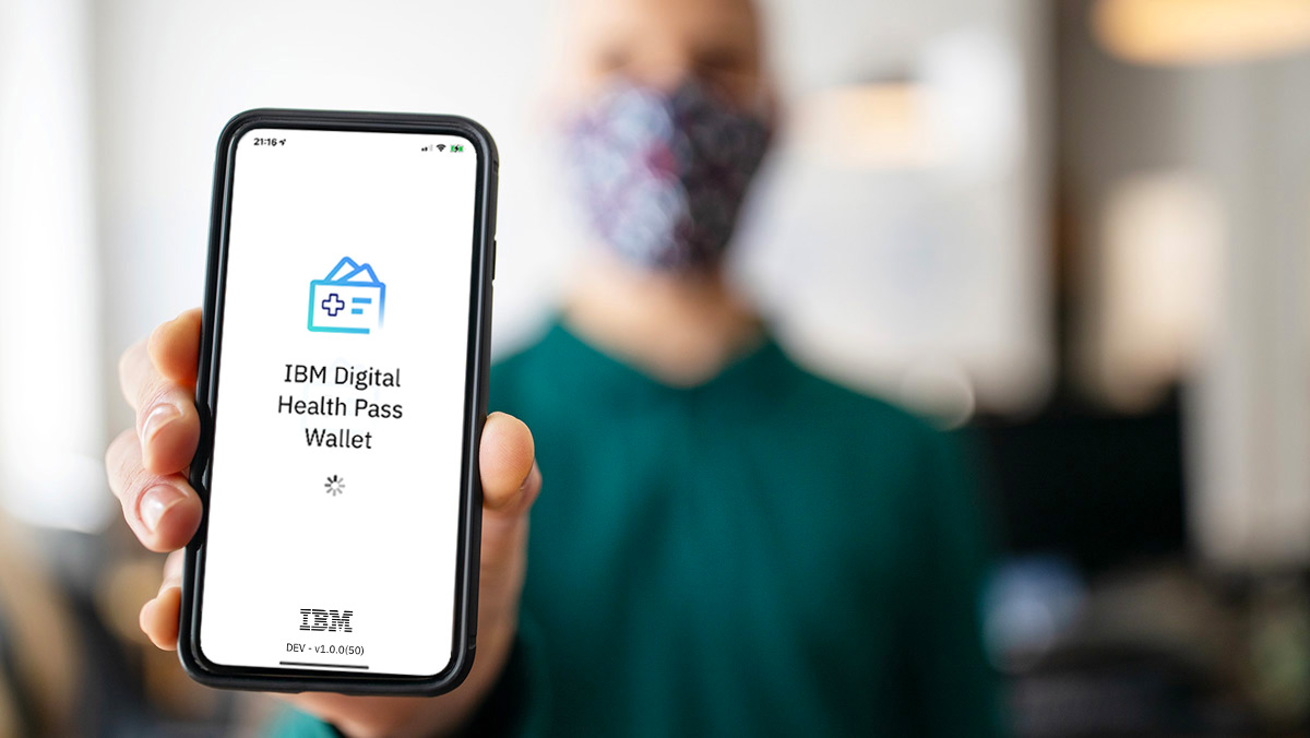 Man with facemask showing IBM Digital Health Pass Wallet app on a smartphone