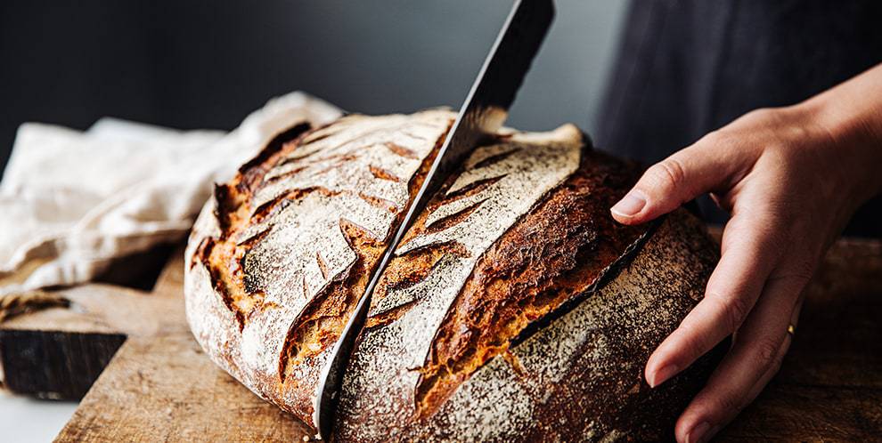 person cutting bread with knife