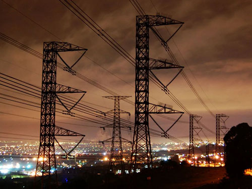 Linee elettriche con la visione notturna della città illuminata sullo sfondo