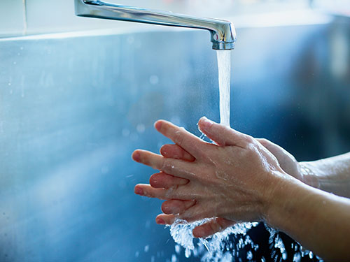 Mani che vengono lavate sotto l'acqua corrente