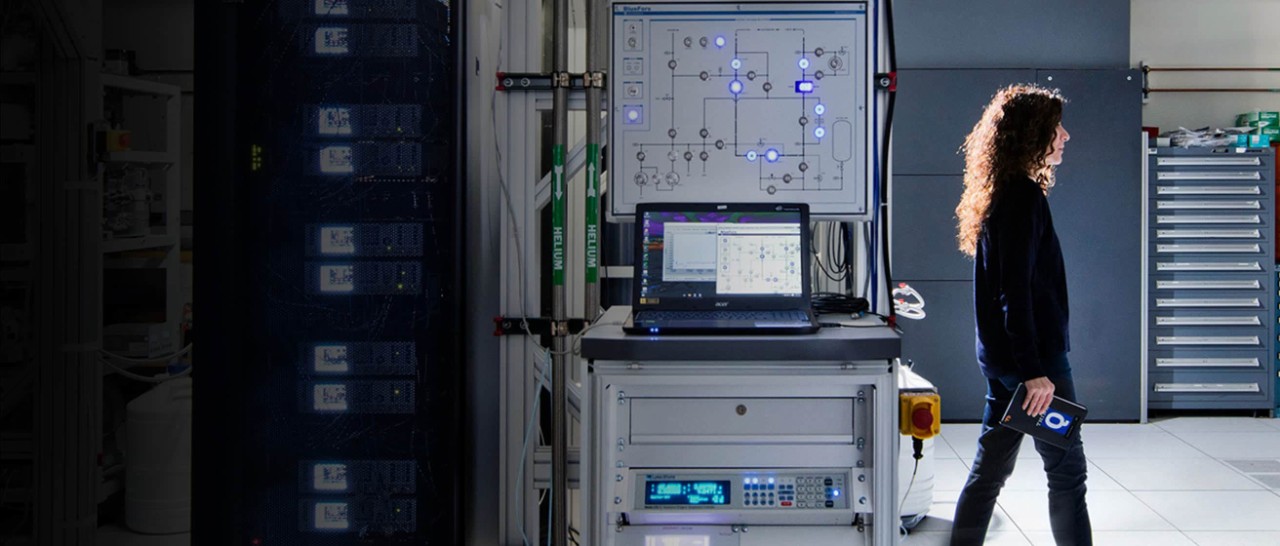 Woman walking in a large server room with a tablet in hand 