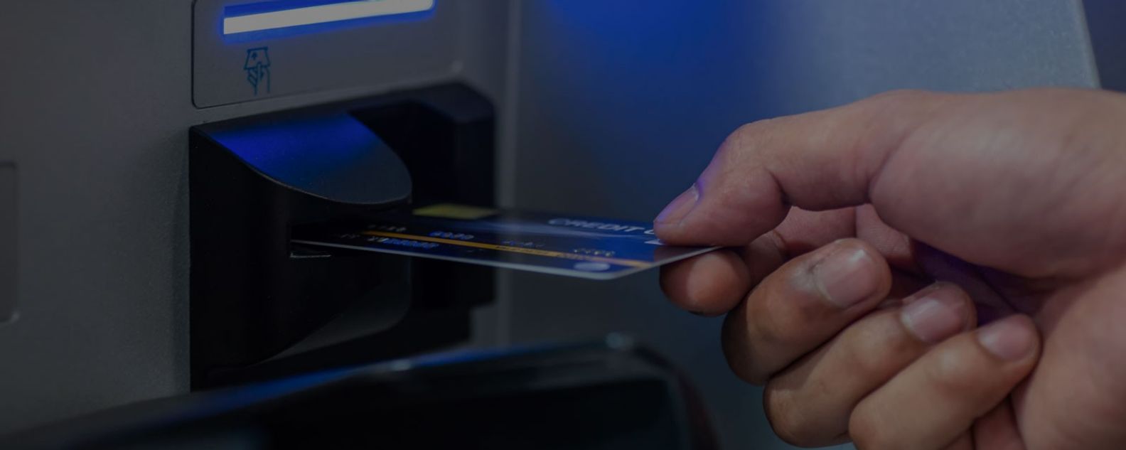 ATM 기계에 직불 카드를 삽입하는 남성