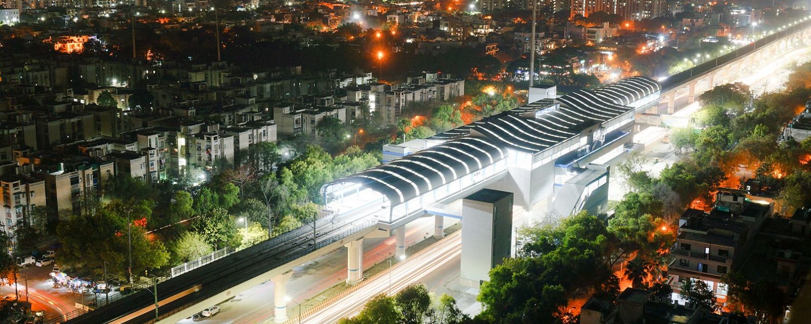 德里地铁站的灯光，背景为城市景观和交通信号灯小径