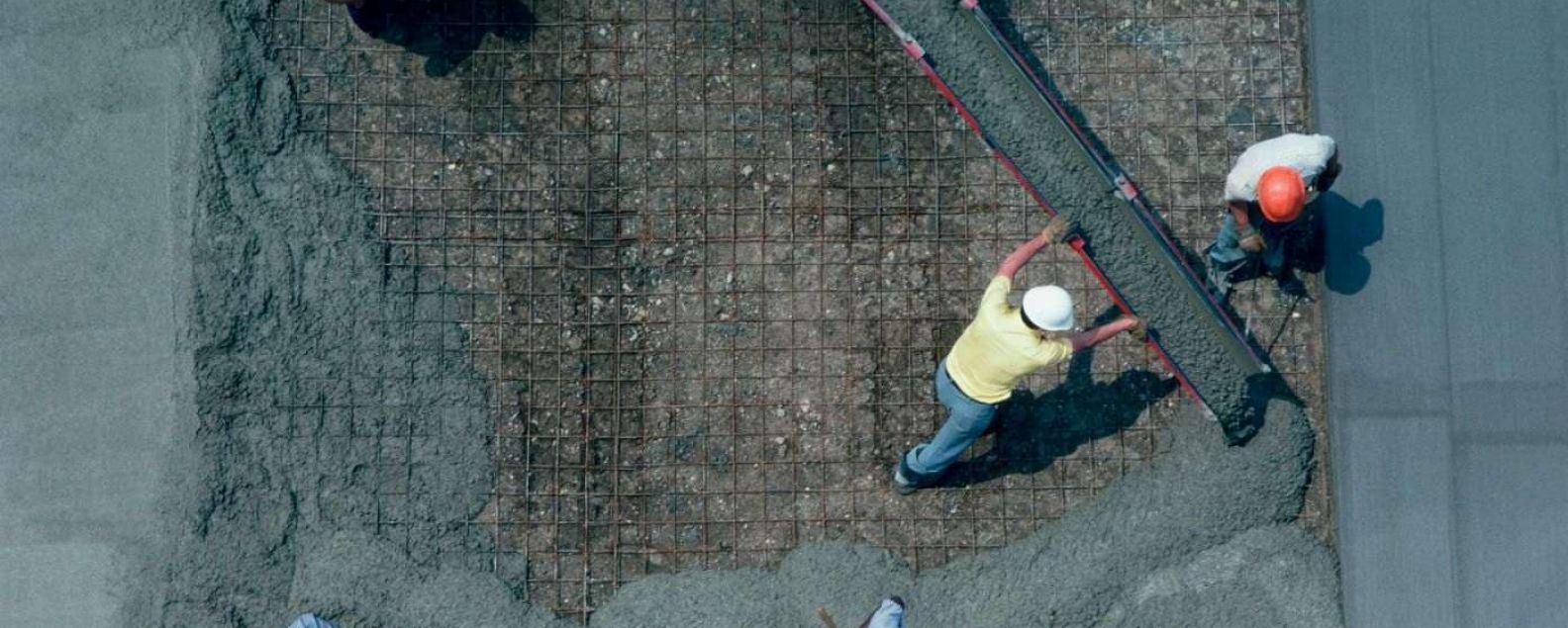 Two construction workers pouring a concrete slab 