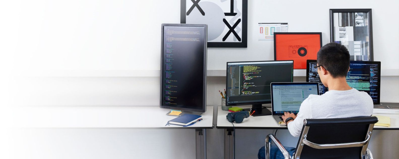 persona trabajando en una computadora y usando tres pantallas de monitor