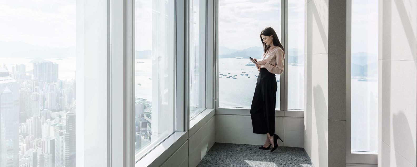 Femme devant une fenêtre utilisant son téléphone portable
