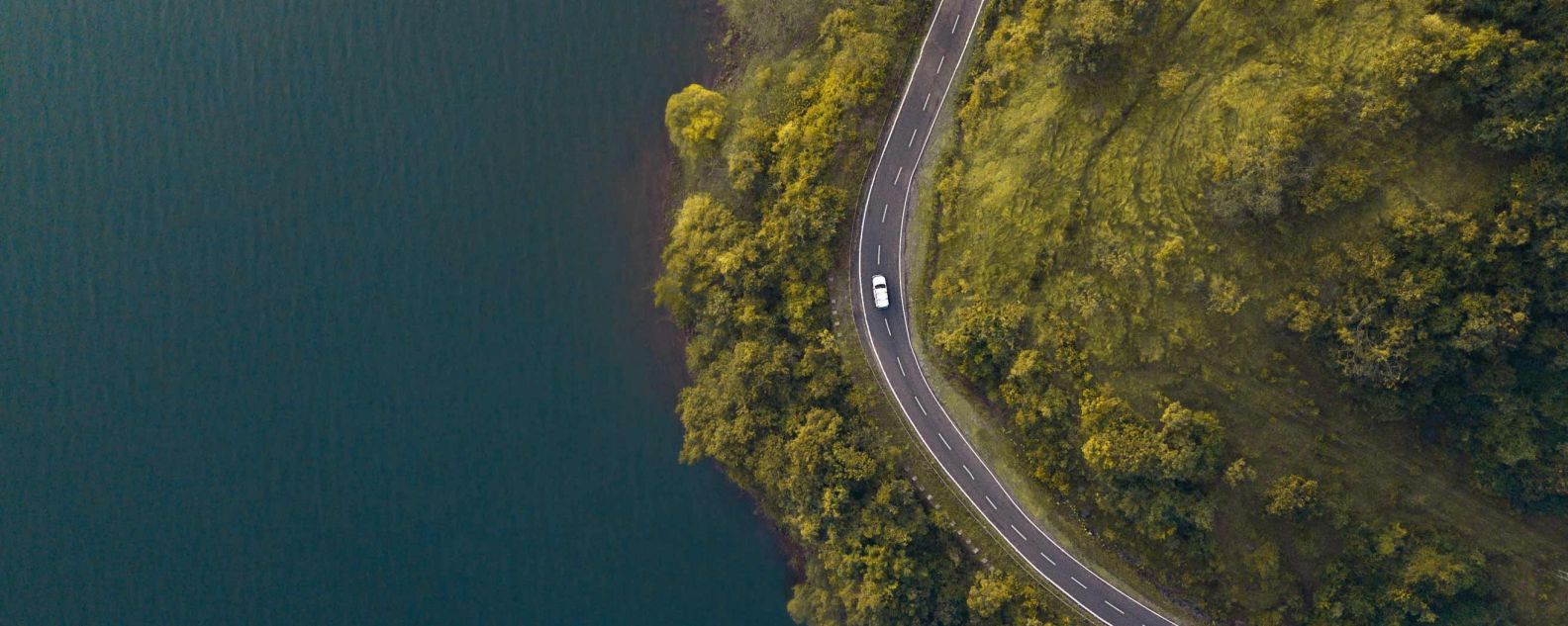 vista aérea de un coche en una carretera sinuosa rodeada de árboles