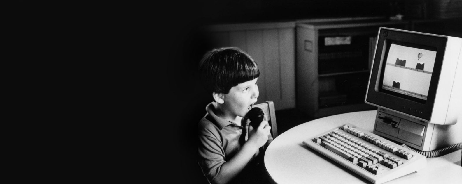 A child speaks into a microphone attached to the PS/2 computer