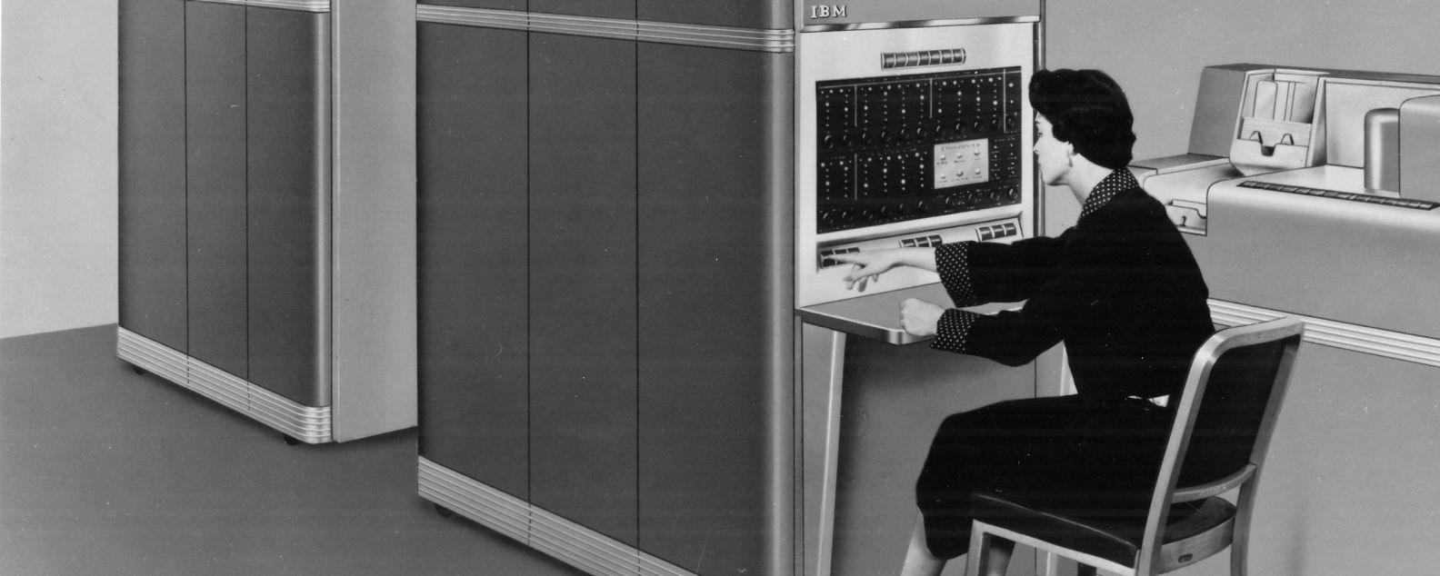 A woman presses a button at the console of a IBM 650 magnetic drum data processing machine, next to an IBM 533 card read punch unit, circa 1953. 