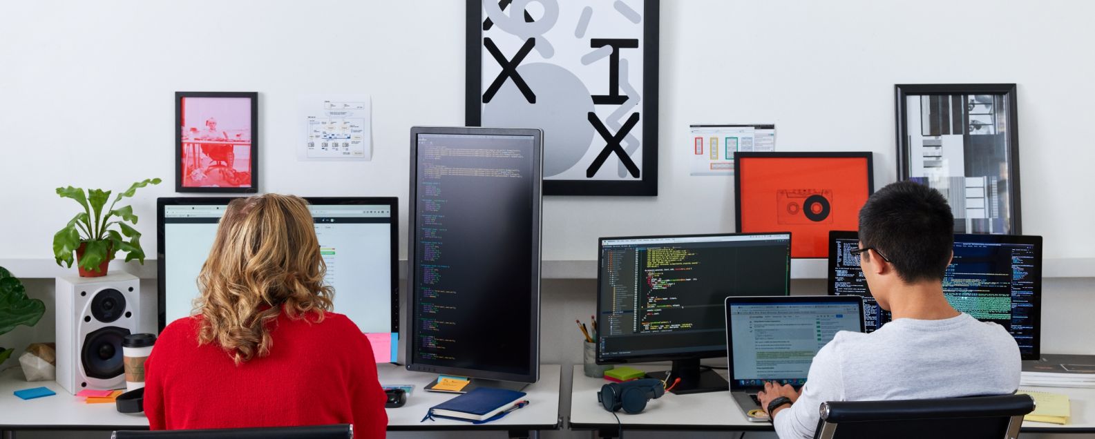 Back view of developer programming on multiple monitors