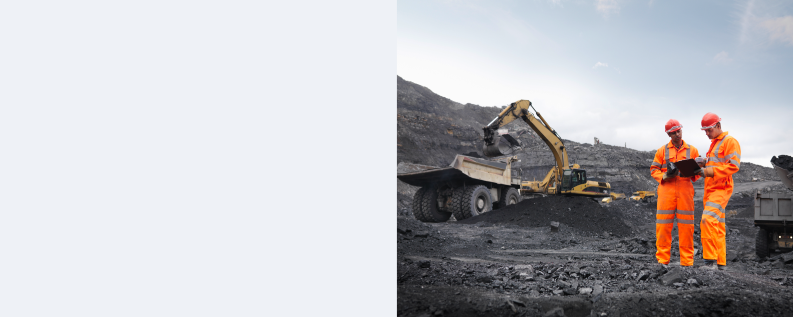 Dos mineros del carbón con equipo de seguridad consultan un dispositivo móvil (tableta)