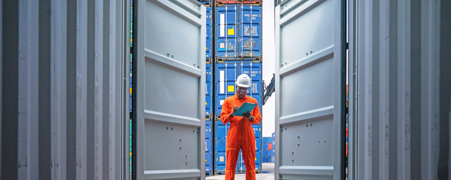Dock worker with clipboard looking inside a shipping container