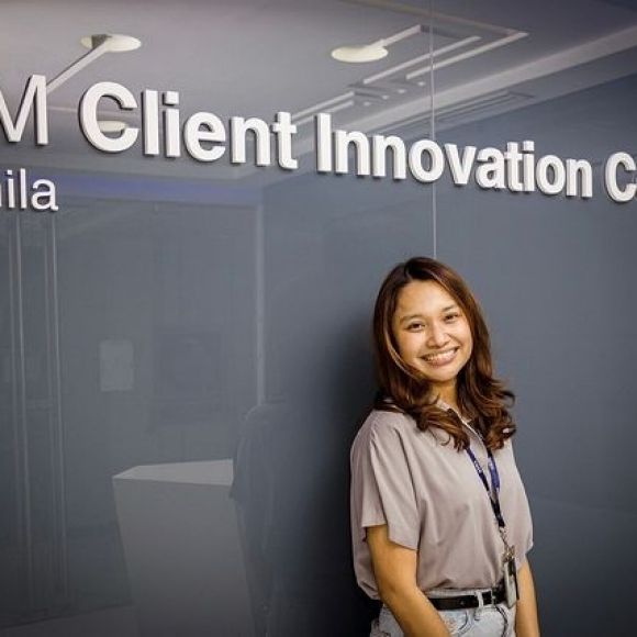 Employee posing next to a wall saying IBM Client Innovation Center