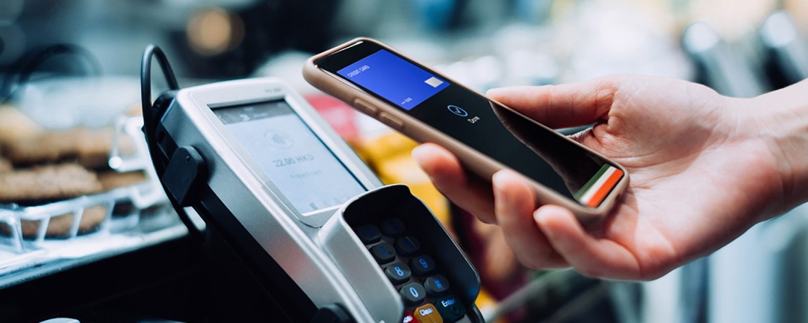 Un dueño de una tienda sonriente que usa una tablet digital para procesar una transacción de tarjeta de crédito con el cliente