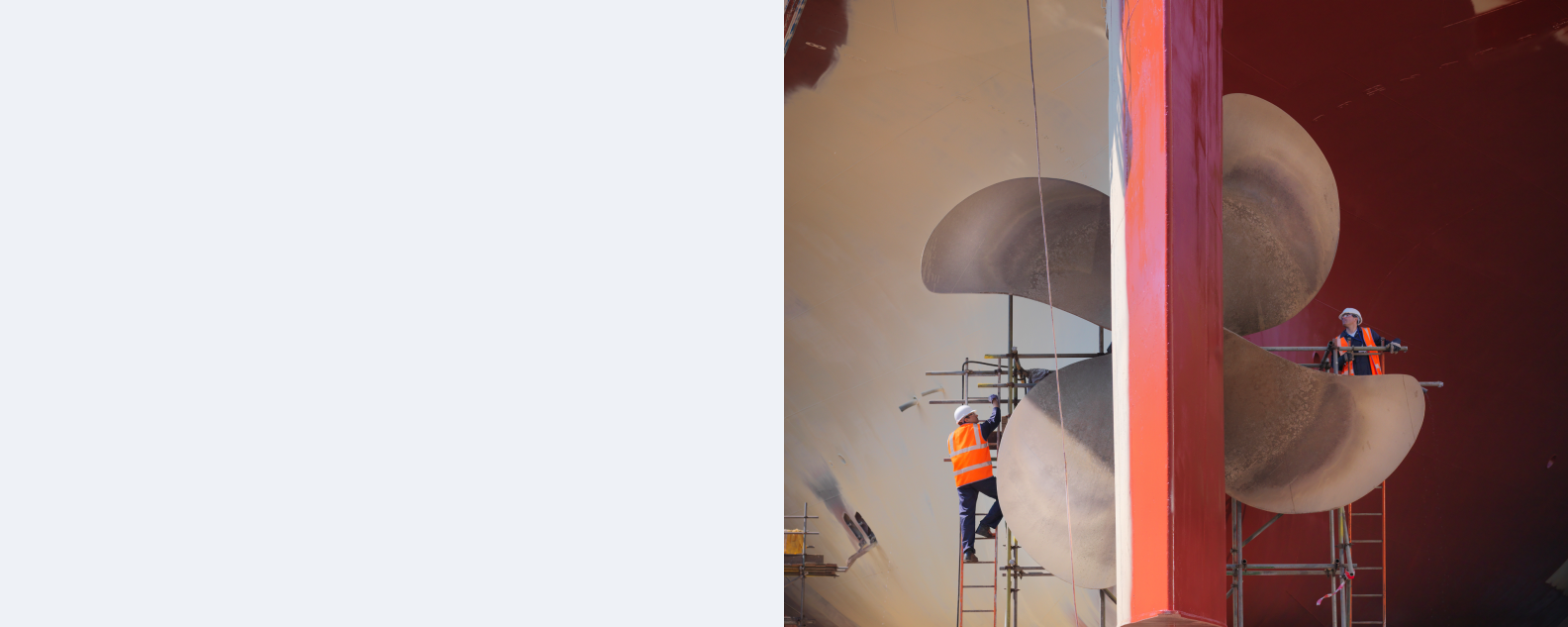 Worker on scaffolding next to ship’s propeller