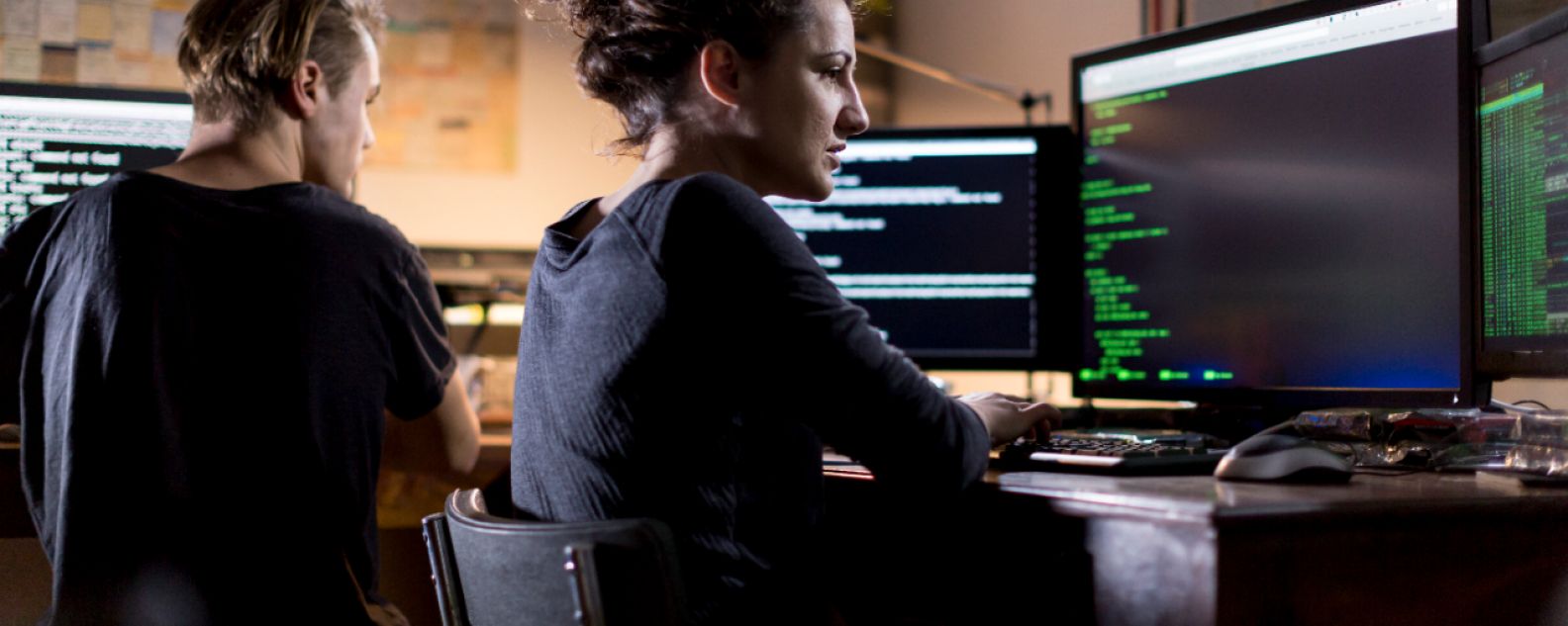 Frau beim Programmieren vor einem großen Monitor