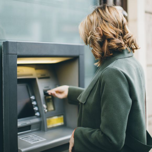 Junge Frau, die einen Geldautomaten bedient