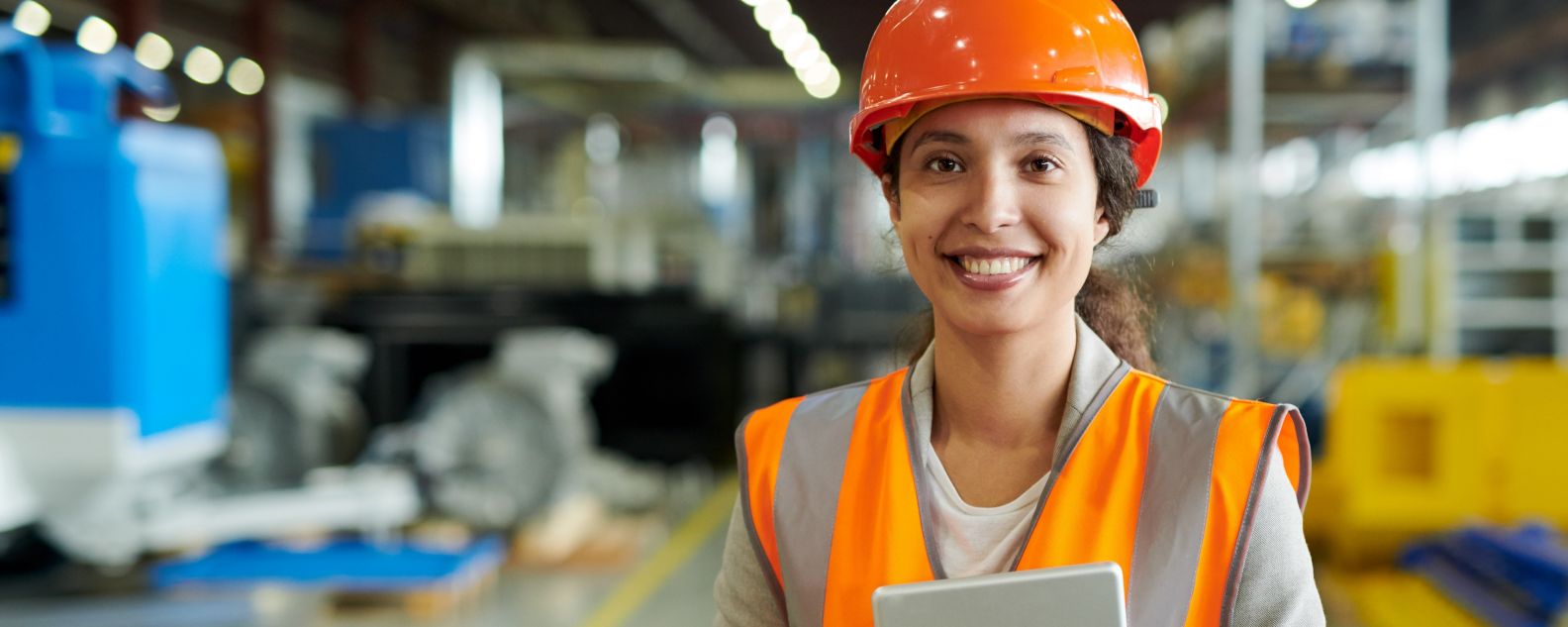 Woman wearing hardhat smiling looking at camera in production workshop